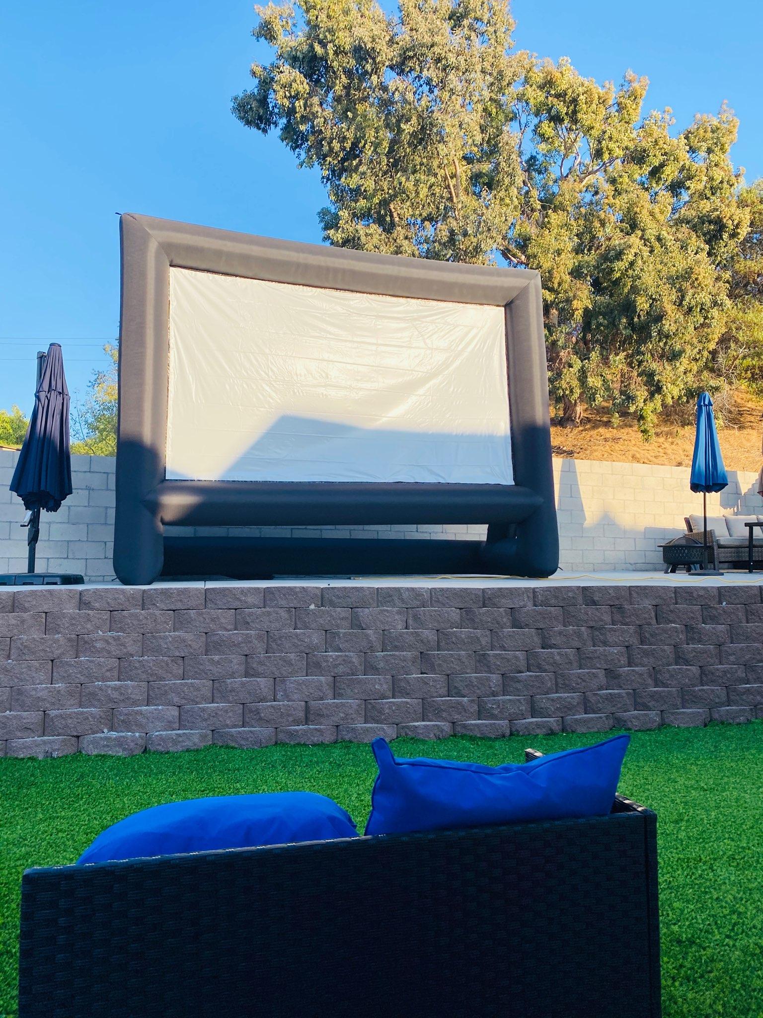 Inflatable movie screen set up in a backyard with blue bean bag seating