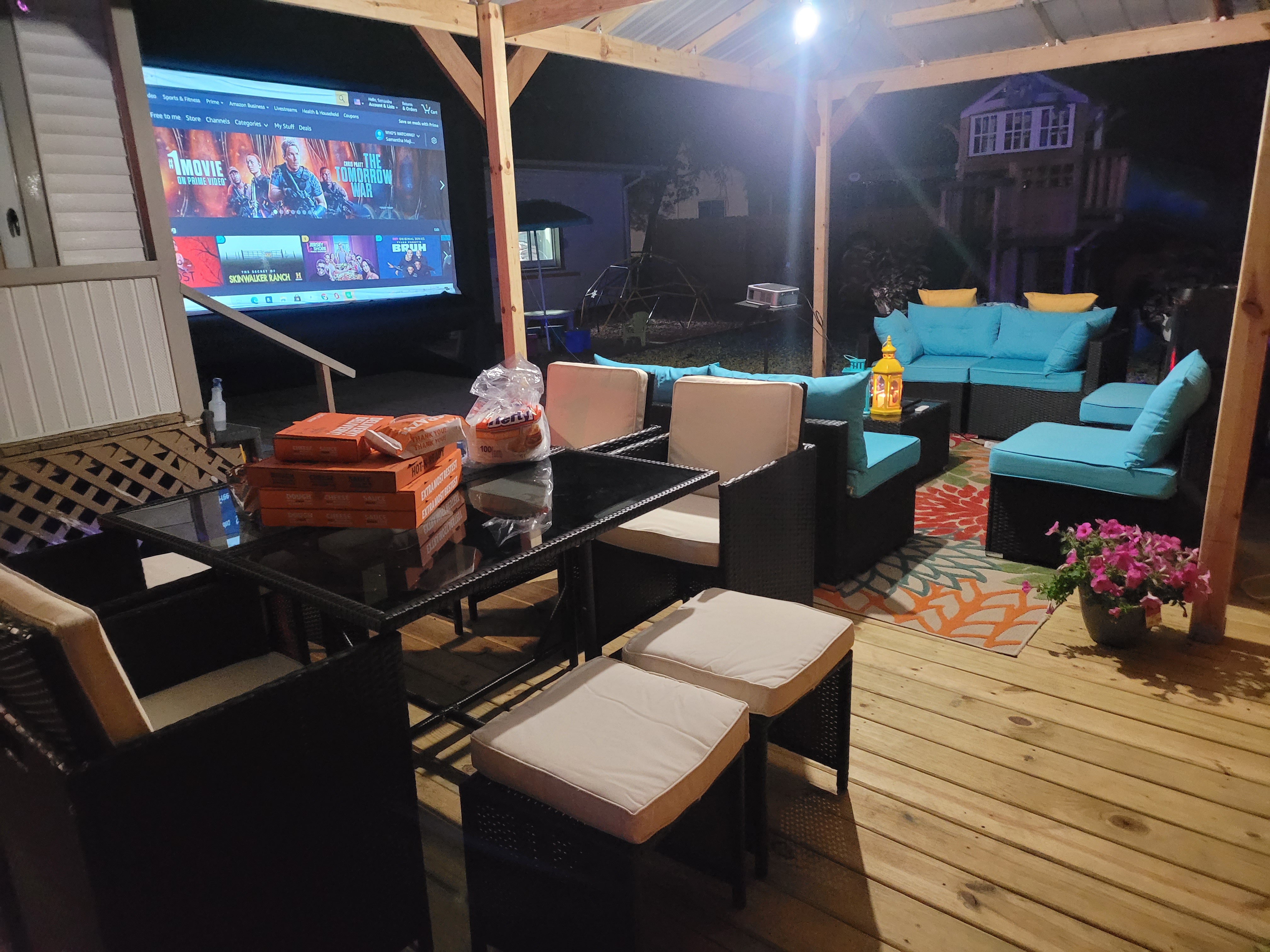 Backyard movie night with screen projecting a movie on a covered outdoor deck
